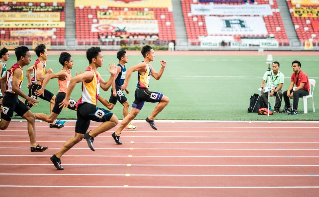 A group of Asian men running on the track for a 200 meter sprint competition