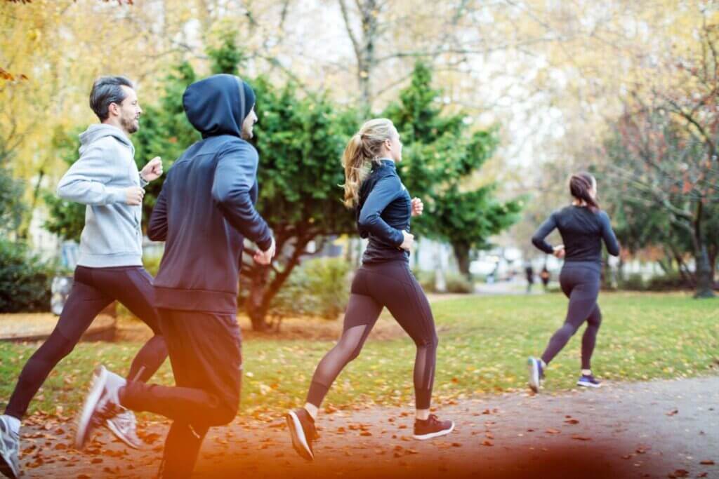 two men and two women with black running outfit, running in a park in the morning