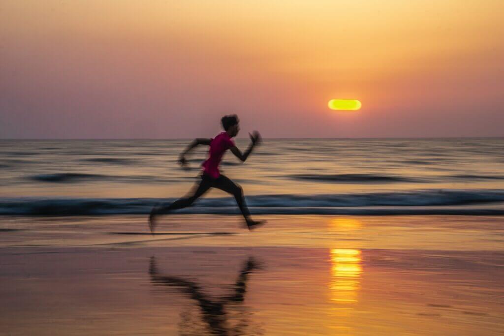 Man running with large stride at the beach
