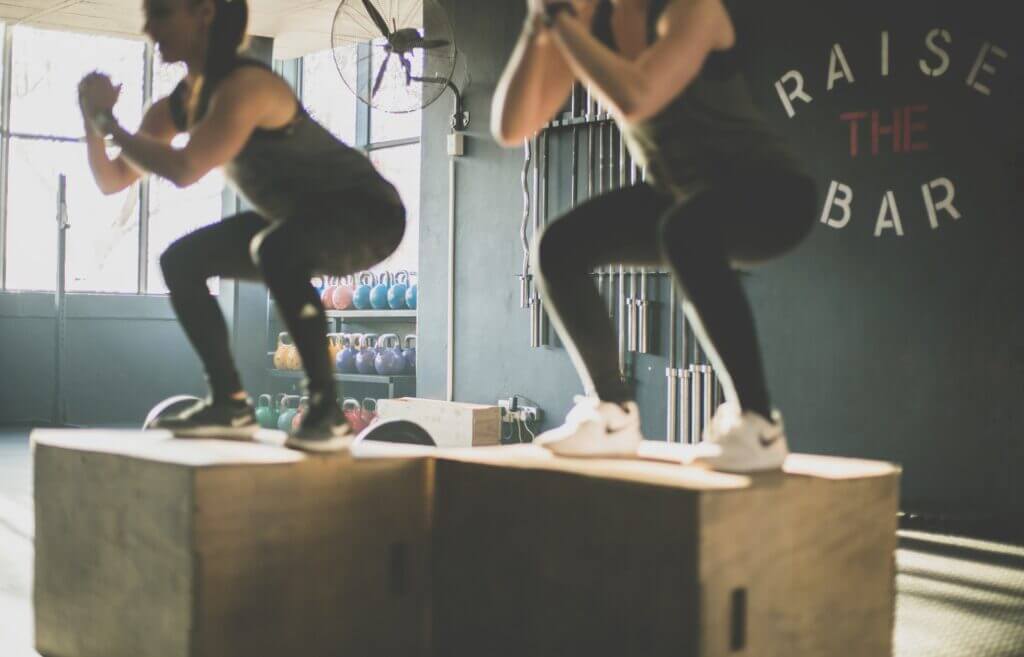 Man and woman doing squat over boxes