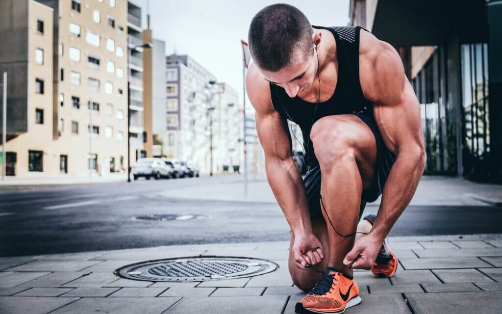 man tying his shoes before running 5 miles a day