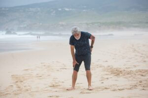 old white man at the beach, having back pains