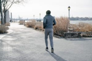 Back view of a man with a grey hoodie running in the morning