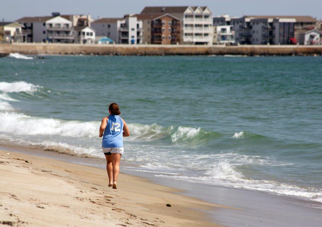 Woman running barefoot at the beach, training for a race