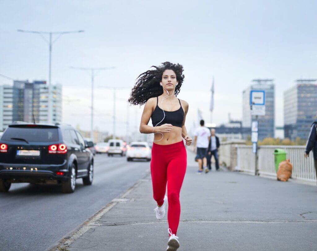 Woman with red pants running in the side of the road