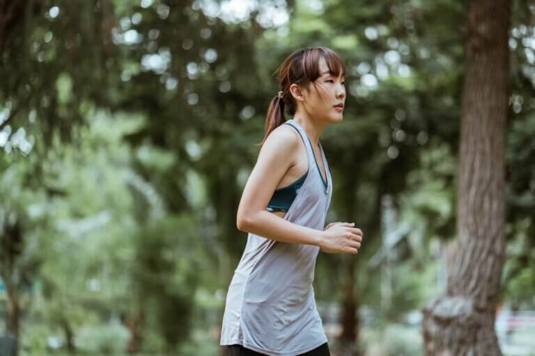Slim sportswoman jogging in green park
