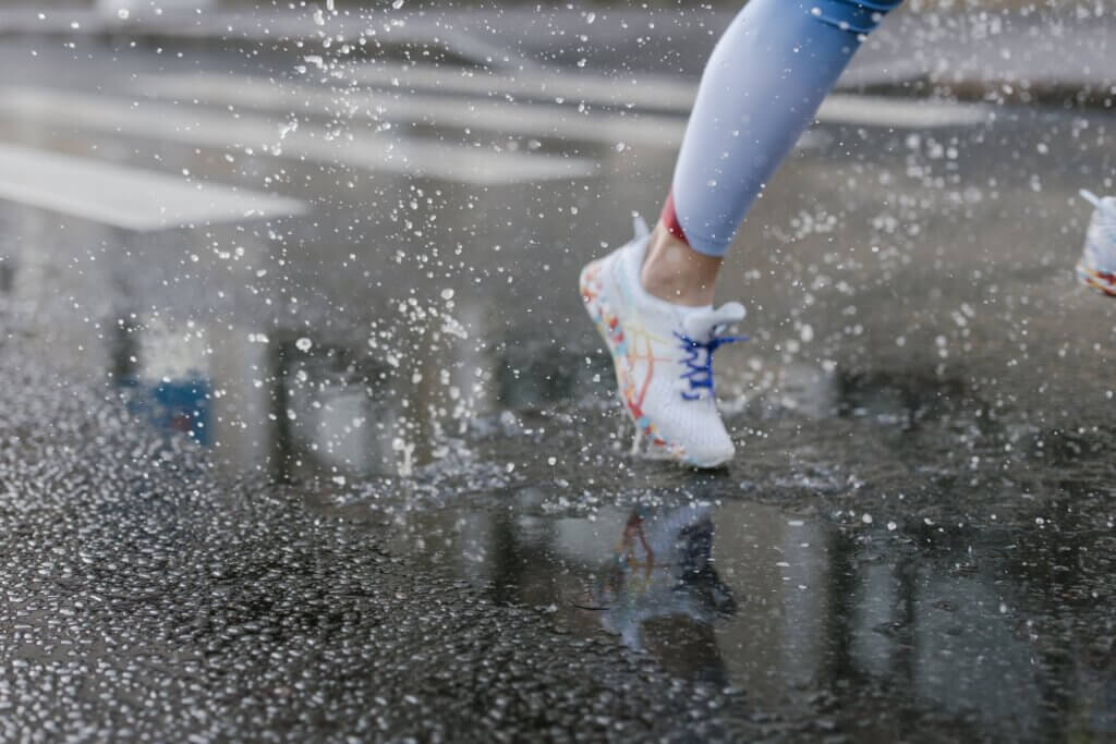 A Person Running  with tennis shoes on Wet Road