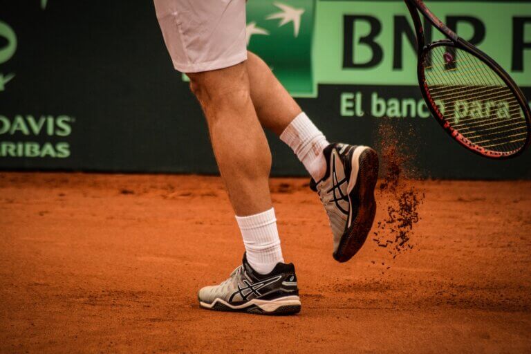Man Wearing Black-and-white Asics Tennis Shoes Holding Racket